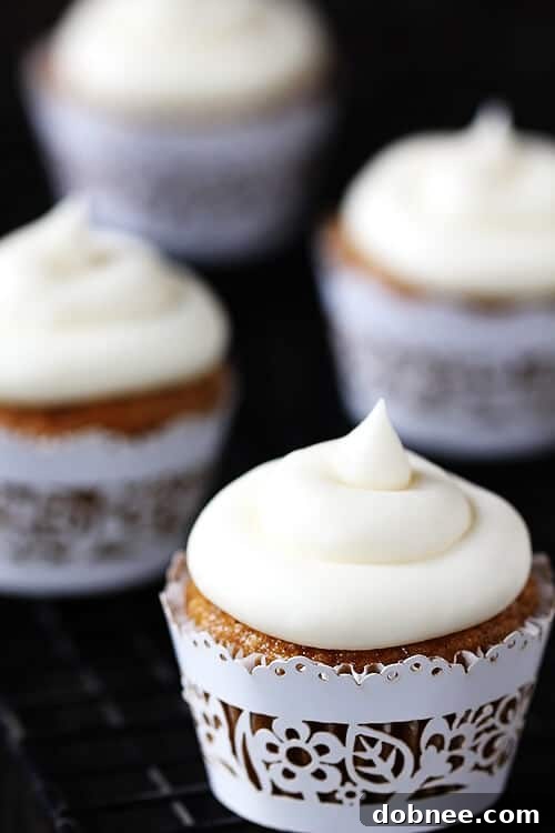 Close-up of a Spiced Butternut Squash Cupcake topped with generous Maple Cream Cheese Frosting and a sprinkle of cinnamon.
