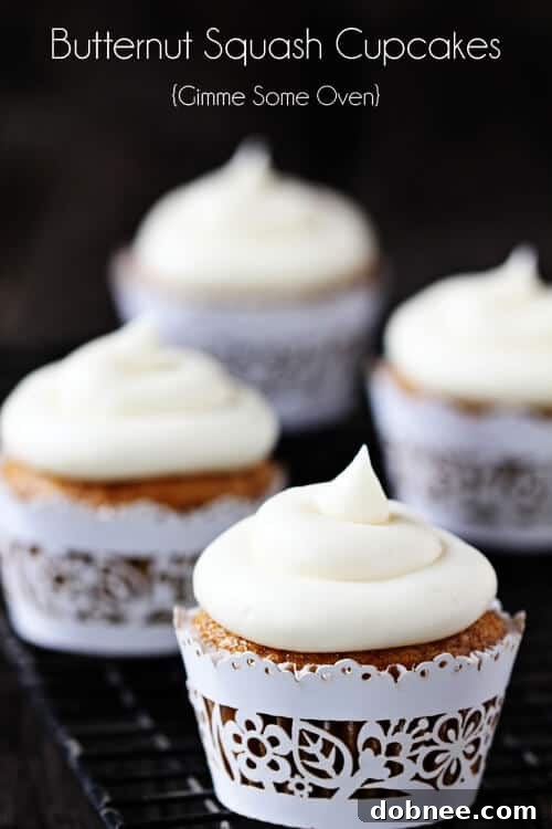 Two Spiced Butternut Squash Cupcakes with Maple Cream Cheese Frosting on a wooden board, ready to be enjoyed.