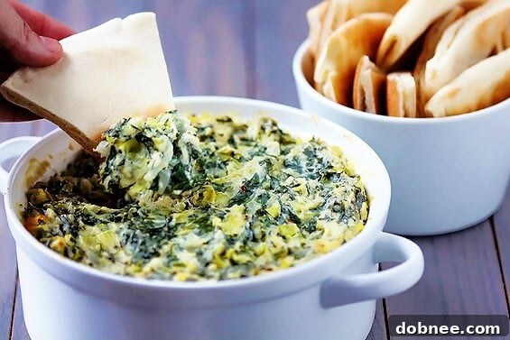 A perfectly baked, bubbly Spinach Artichoke Dip in a rustic ceramic dish, garnished with fresh parsley.