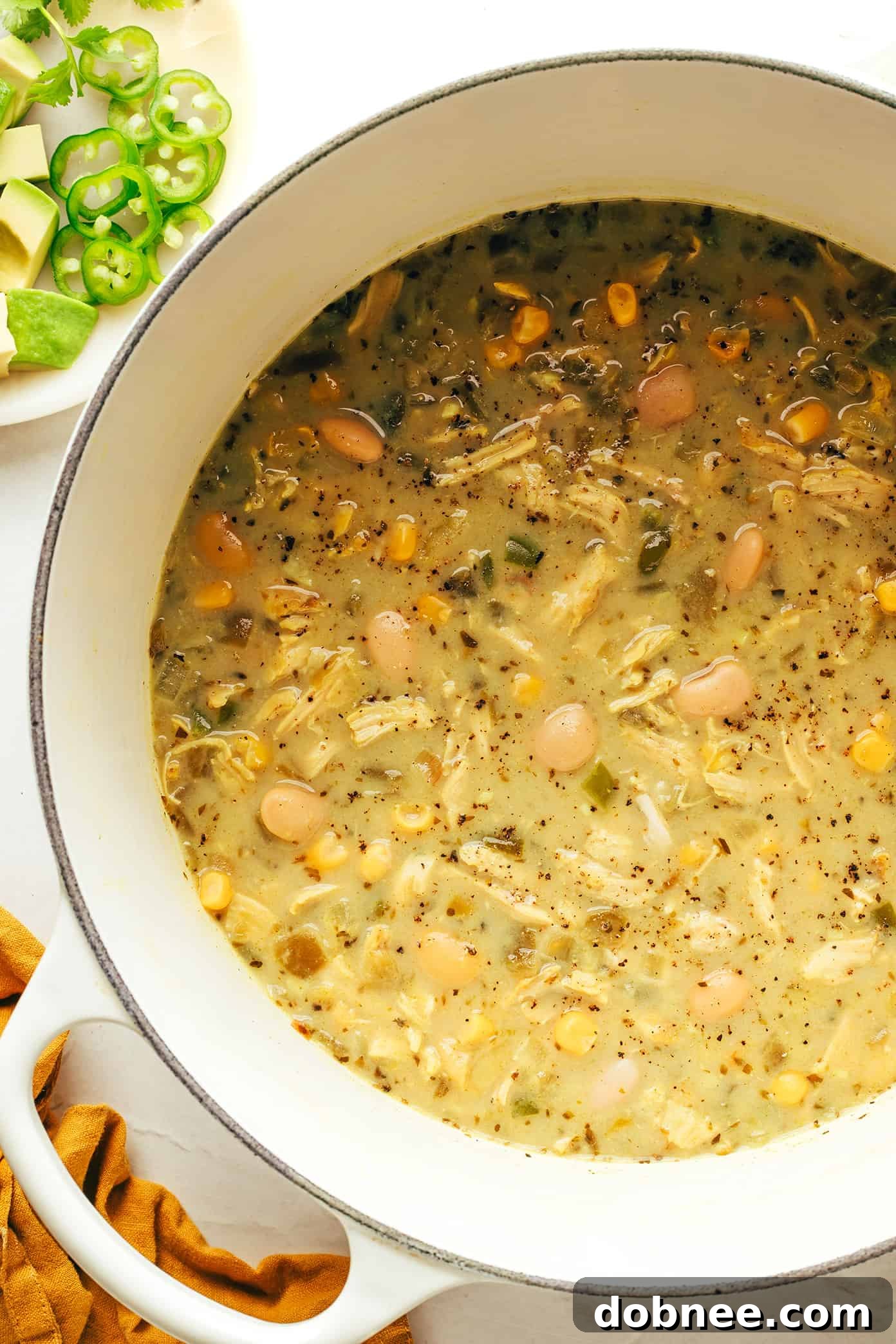 A large pot of white chicken chili simmering on a stovetop, ready to be served.