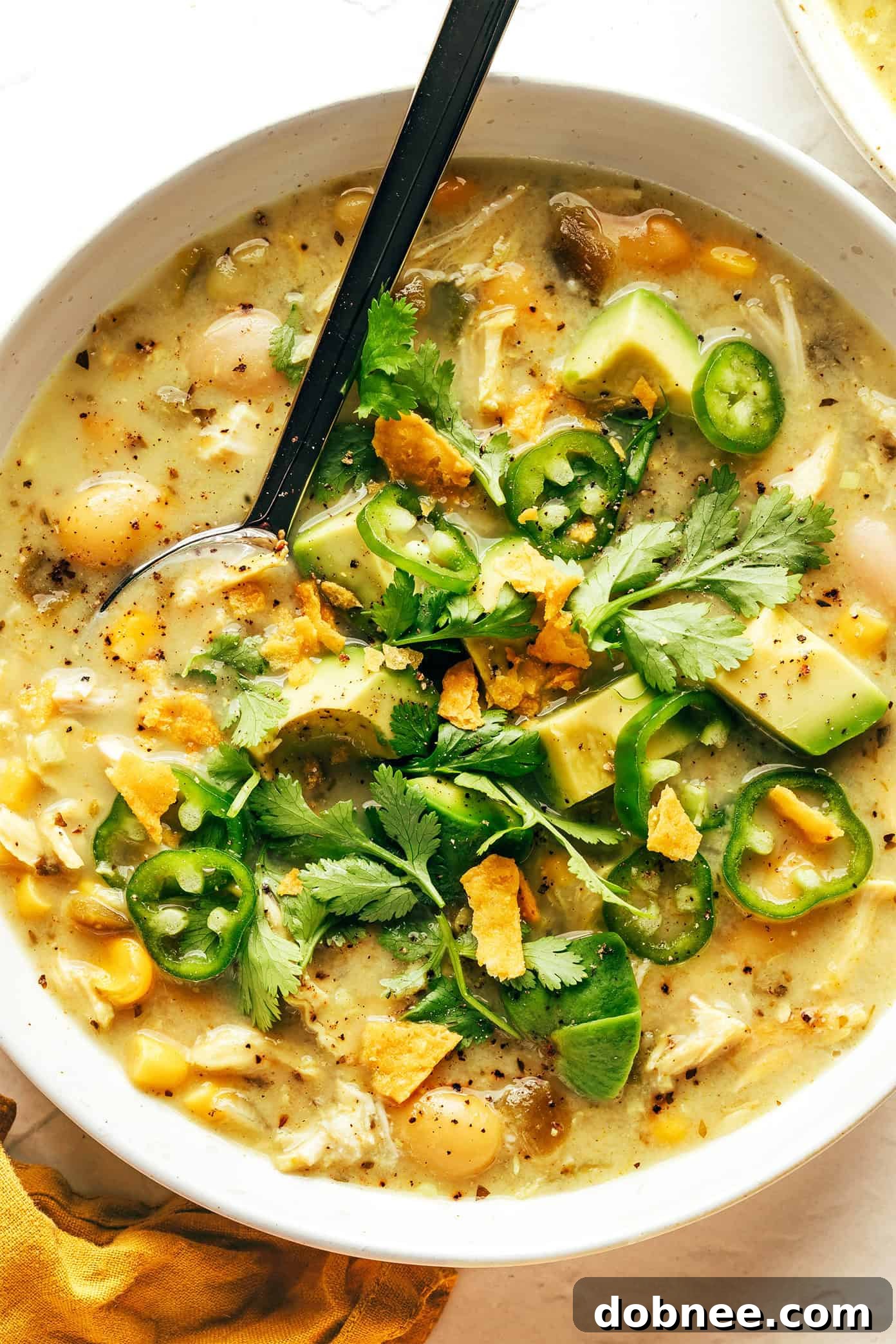 A final beautifully garnished bowl of white chicken chili, ready to eat.