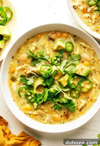 A bowl of creamy white chicken chili with various toppings, ready to be served.
