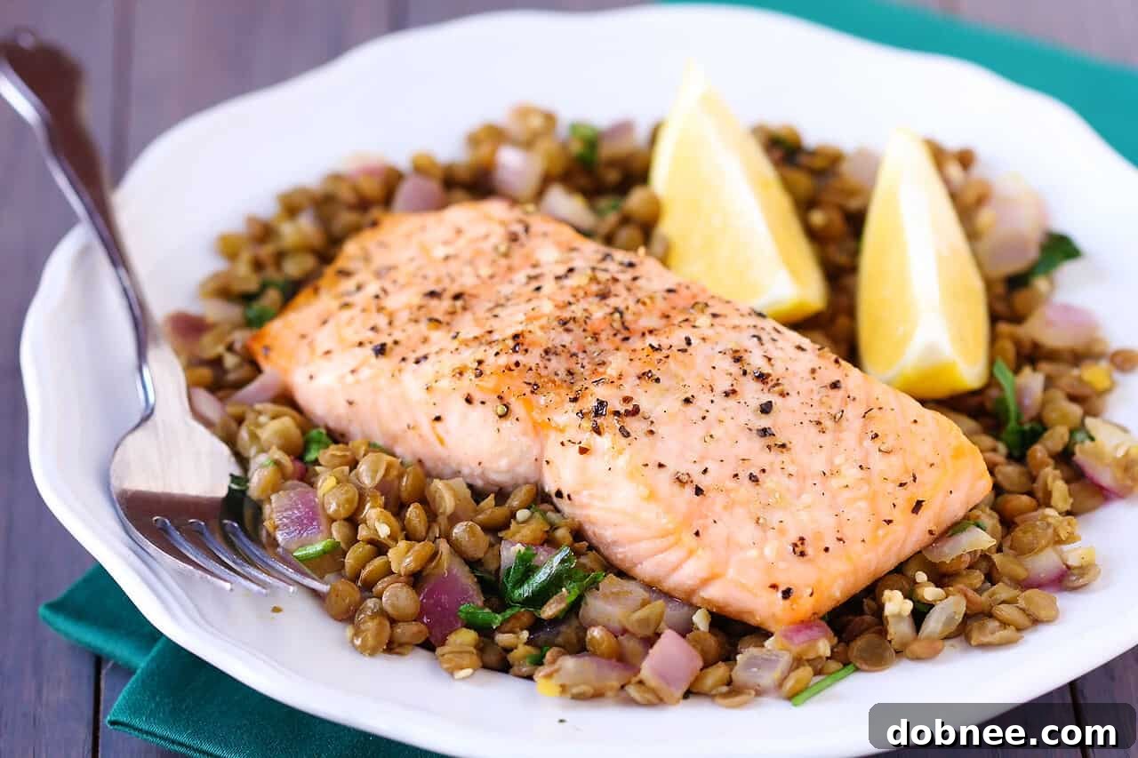 Perfectly cooked baked salmon fillet on a bed of seasoned lentils, ready to be served.
