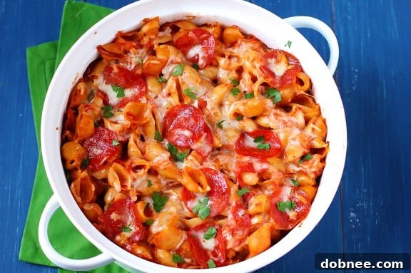 A bubbling, cheesy Pepperoni Pasta Bake, fresh from the oven, garnished with fresh basil. A classic comfort food recipe perfect for family dinners.