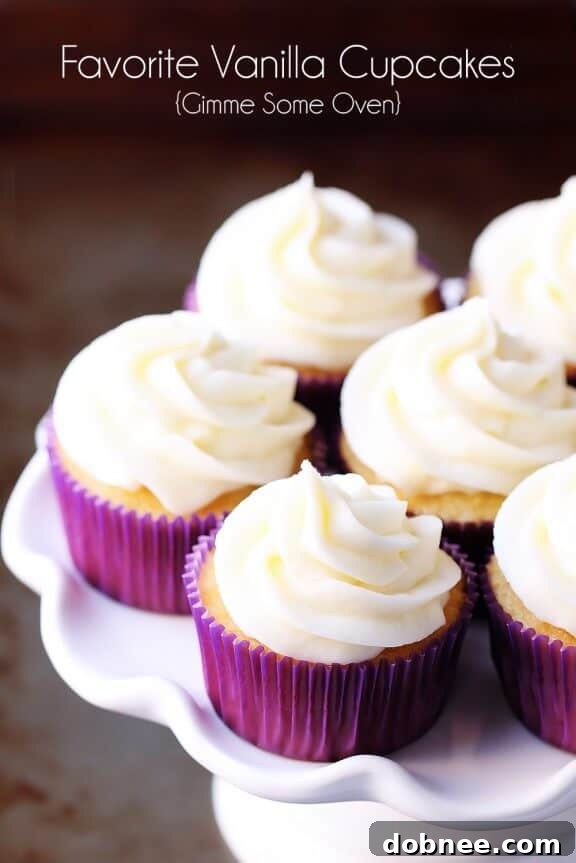A beautifully decorated vanilla cupcake with a tall swirl of vanilla buttercream and a delicate sugar pearl.