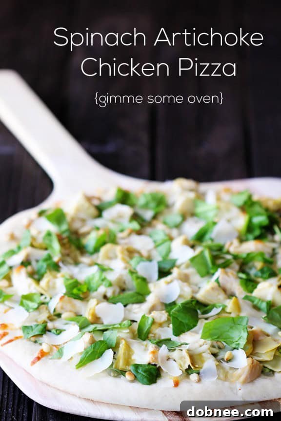 Close-up of a slice of Spinach Artichoke Chicken Pizza, showing the melted cheese, spinach, and artichokes.