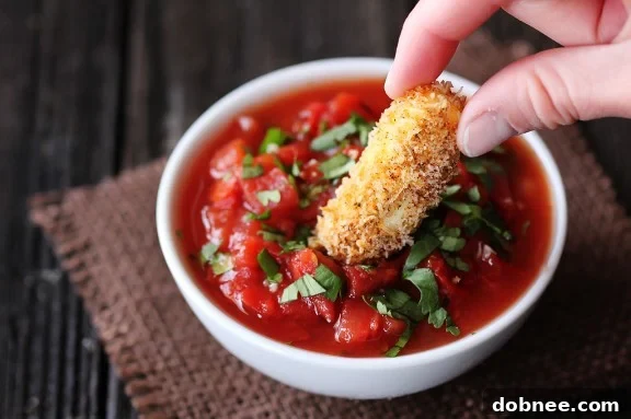 Delicious Baked Mexican Mozzarella Cheese Sticks, golden brown and crispy, served with a vibrant red salsa for dipping.