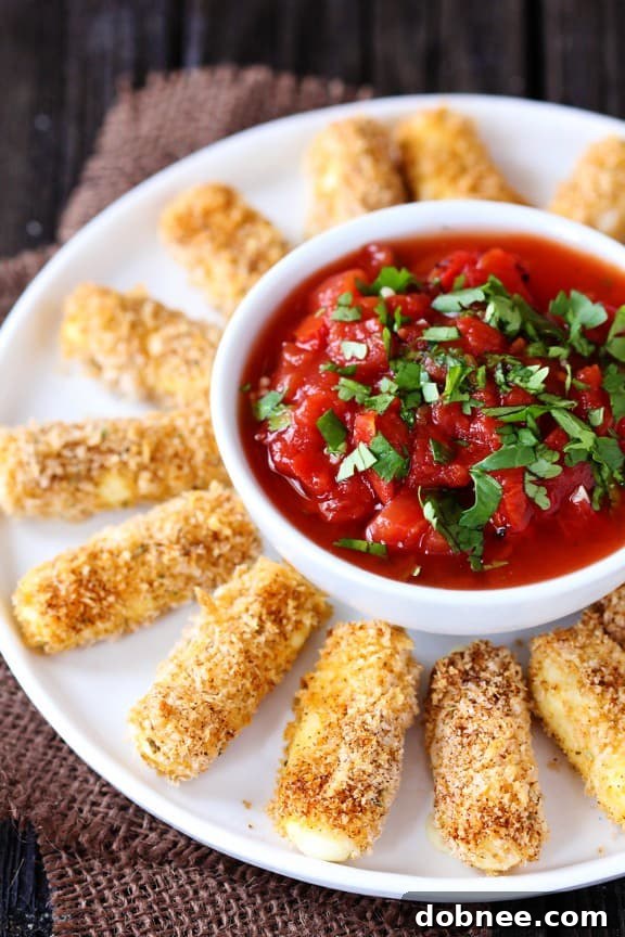 Close-up of golden baked Mexican mozzarella cheese sticks with a bowl of fresh salsa, emphasizing their crispy texture.