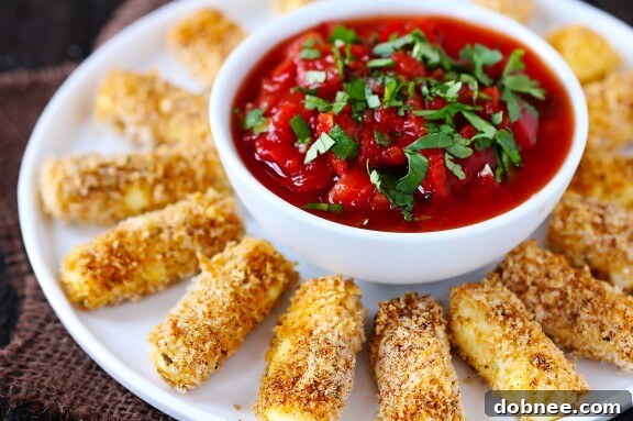 Process image: A breaded mozzarella stick being placed on a baking sheet, ready for the oven, highlighting the meticulous preparation.