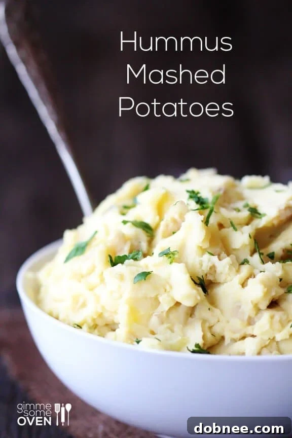 Close-up of fluffy Hummus Mashed Potatoes in a white bowl, garnished with fresh herbs. The texture is smooth and inviting.