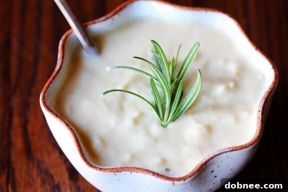A rustic bowl of creamy potato and pear soup, garnished with herbs, perfect for a cozy winter meal.