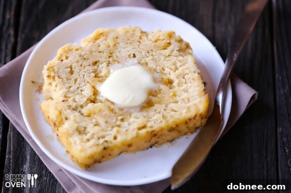 A close-up of a slice of Whole Wheat Garlic & Herb Beer Bread, revealing the herbs and garlic.