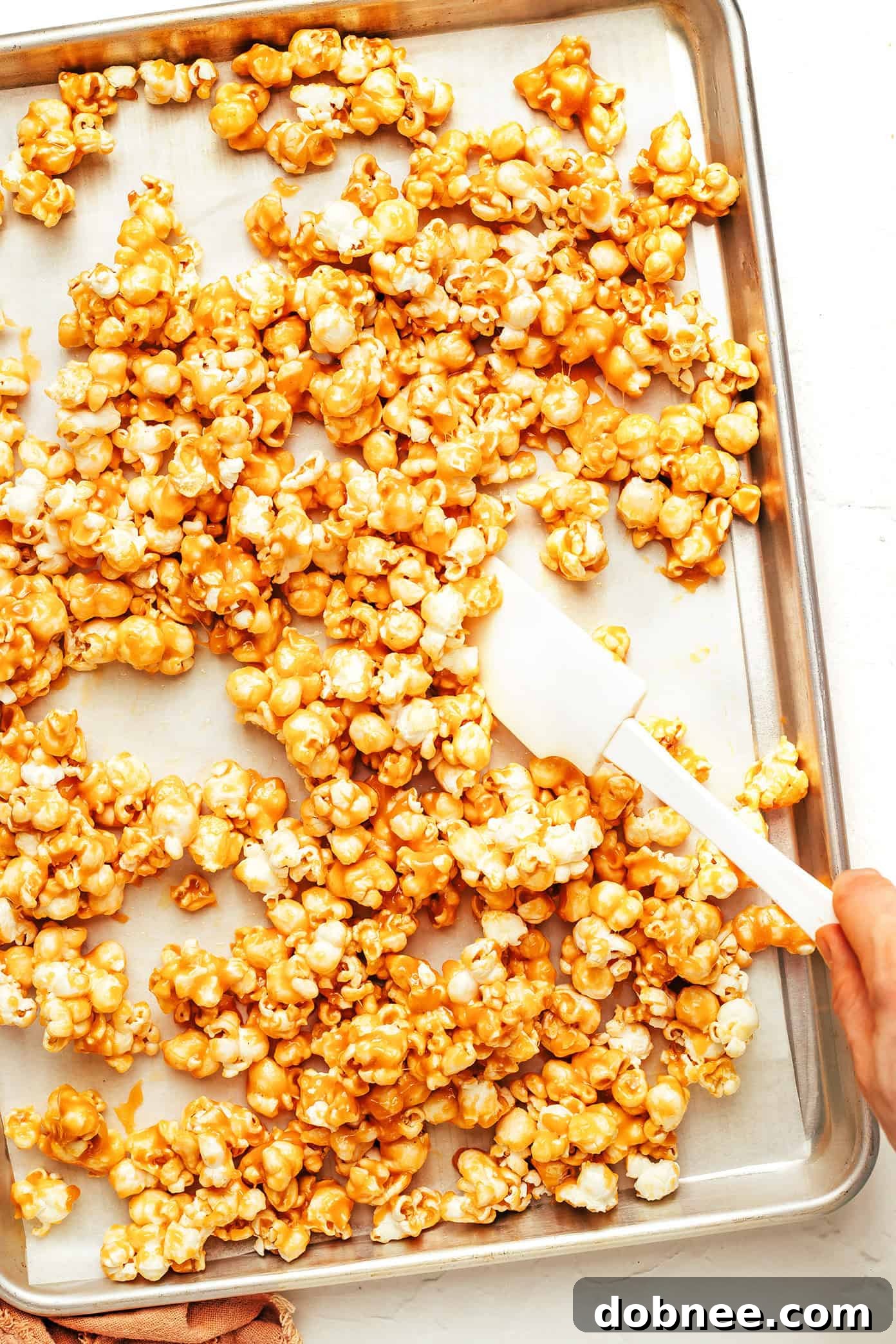 A delicious batch of homemade caramel corn cooling on a baking sheet.