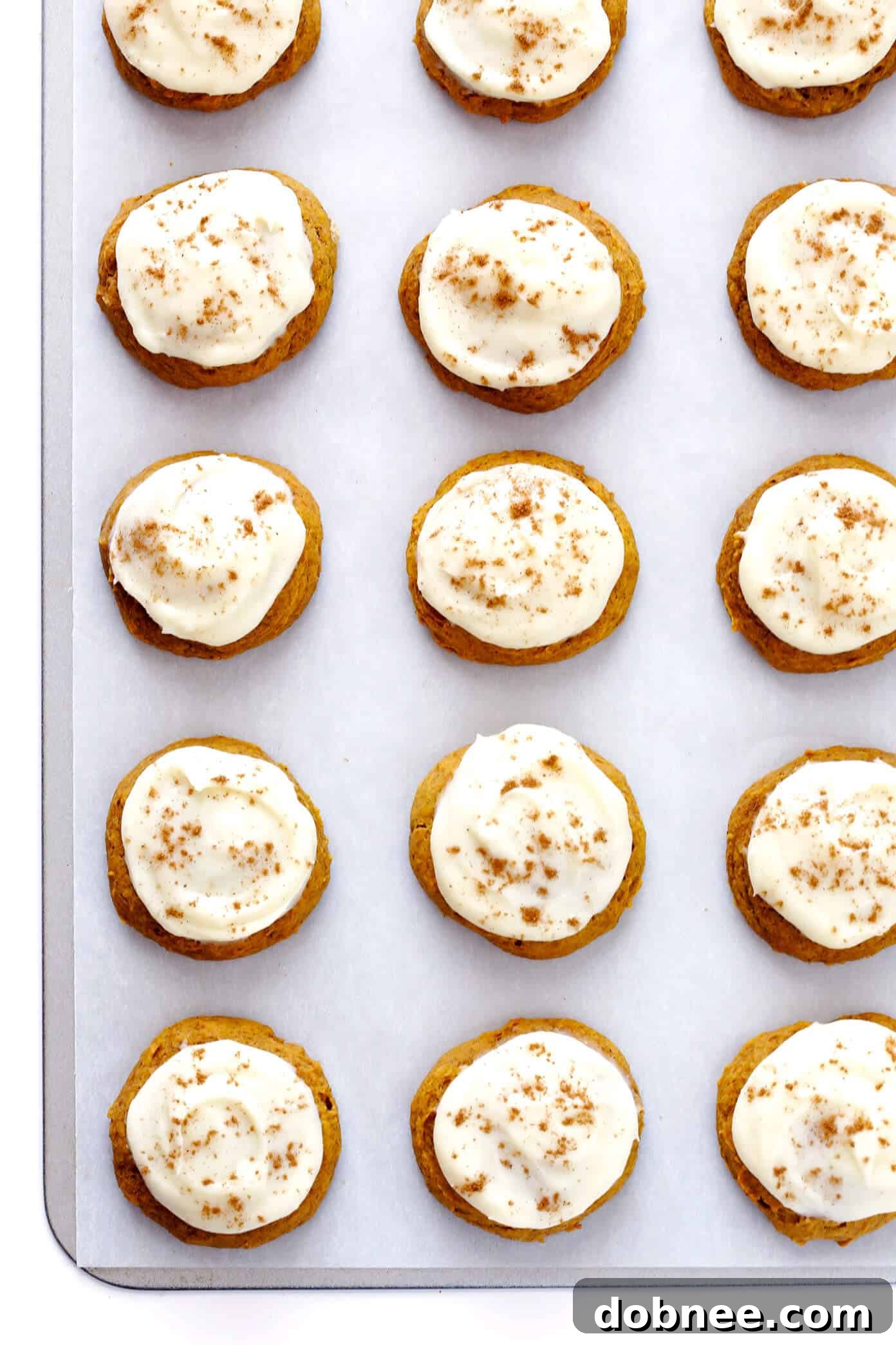 A large, tempting stack of freshly baked soft pumpkin cookies, generously frosted with creamy cream cheese icing, symbolizing the joy of fall baking.