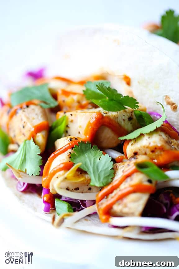 Overhead shot of two Thai Chicken Tacos on a wooden board, with fresh lime and cilantro