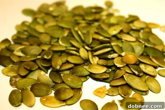 Raw hulled pumpkin seeds (pepitas) ready for seasoning and roasting in a bowl.