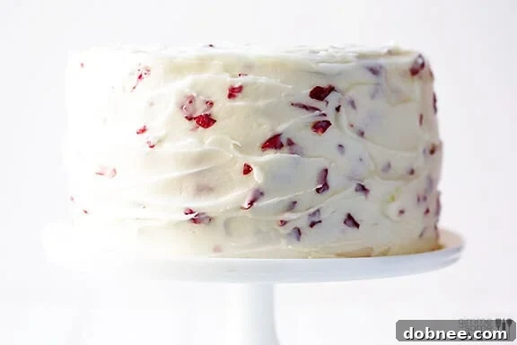 Close-up of a slice of Rose Cake showing moist layers, rose-infused frosting, and subtle petal flecks