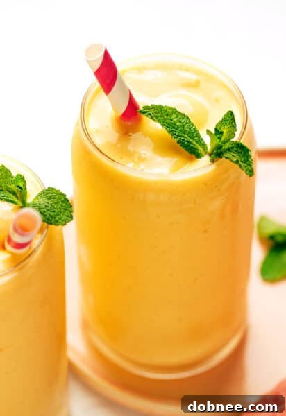 Creamy mango lassi garnished with mint and mango chunks