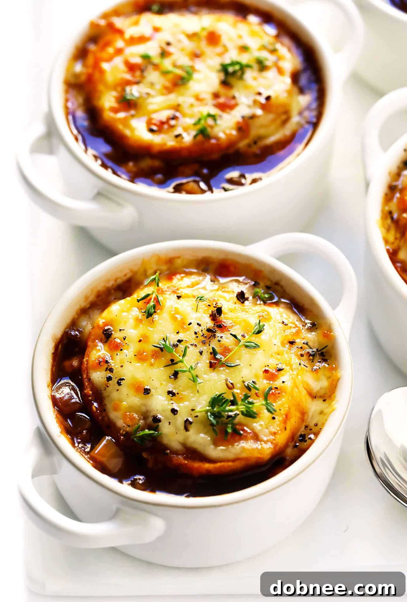French Onion Soup in Bowls with Melted Cheese and Fresh Thyme garnish