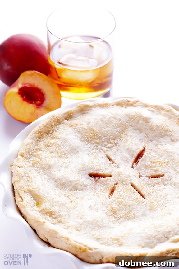 Hand placing the top crust on a Peach Bourbon Pie