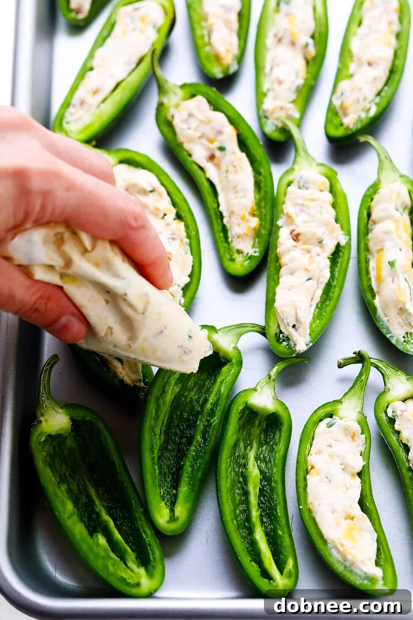 Close-up of baked jalapeño poppers, showing the golden cheese filling and crispy topping.