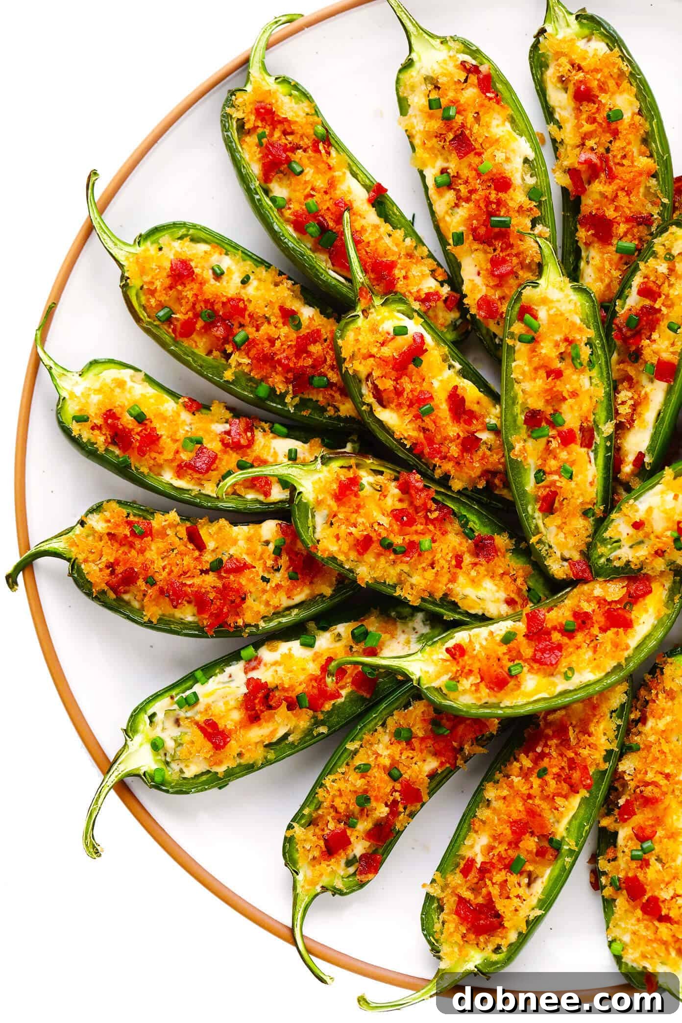 Assortment of freshly baked jalapeño poppers, garnished with fresh herbs and bacon bits.