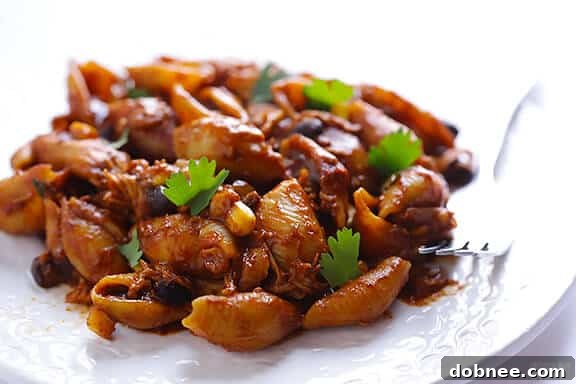 Individual serving of Chicken Enchilada Pasta Bake with avocado and cilantro garnish