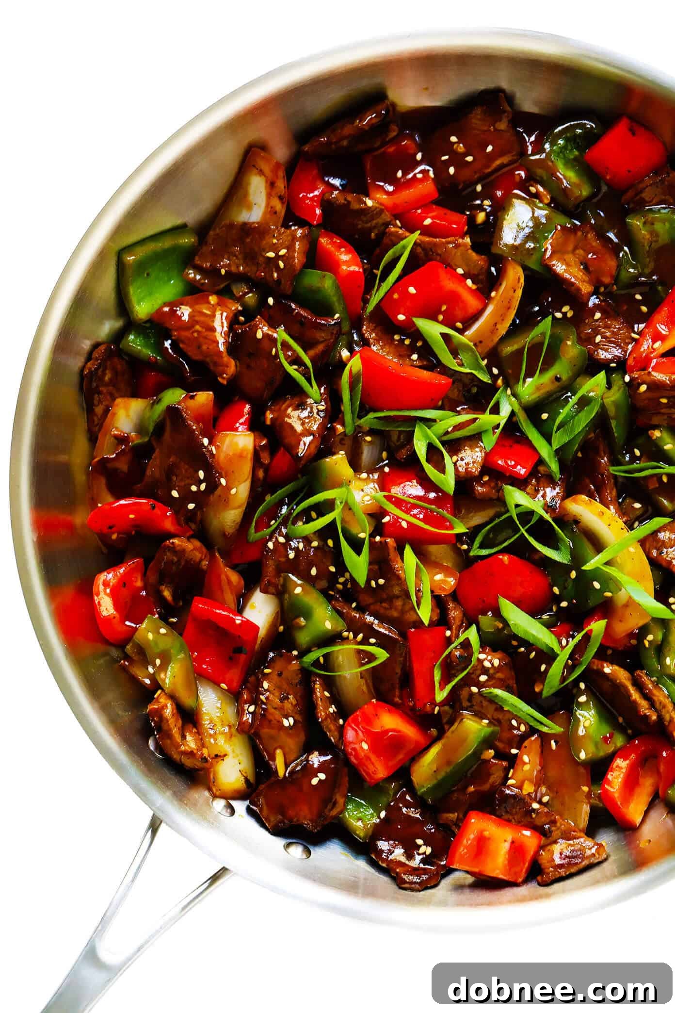 Close-up of freshly cooked Easy Pepper Steak, showing beef strips, green onions, and colorful peppers.