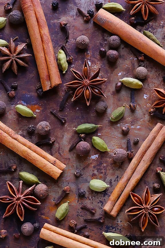 A saucepan filled with water and an assortment of whole chai spices simmering on a stovetop.