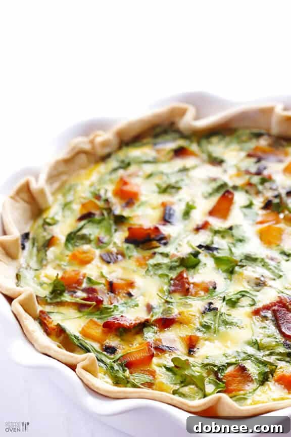 A slice of Butternut Squash, Arugula, and Bacon Quiche on a plate, ready to serve