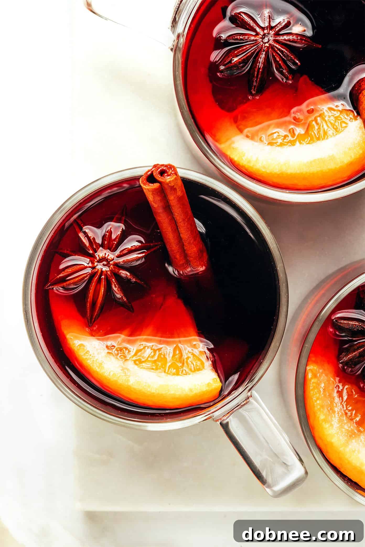 Warm Mulled Wine Served in Glass Mugs with Orange and Cinnamon Garnish