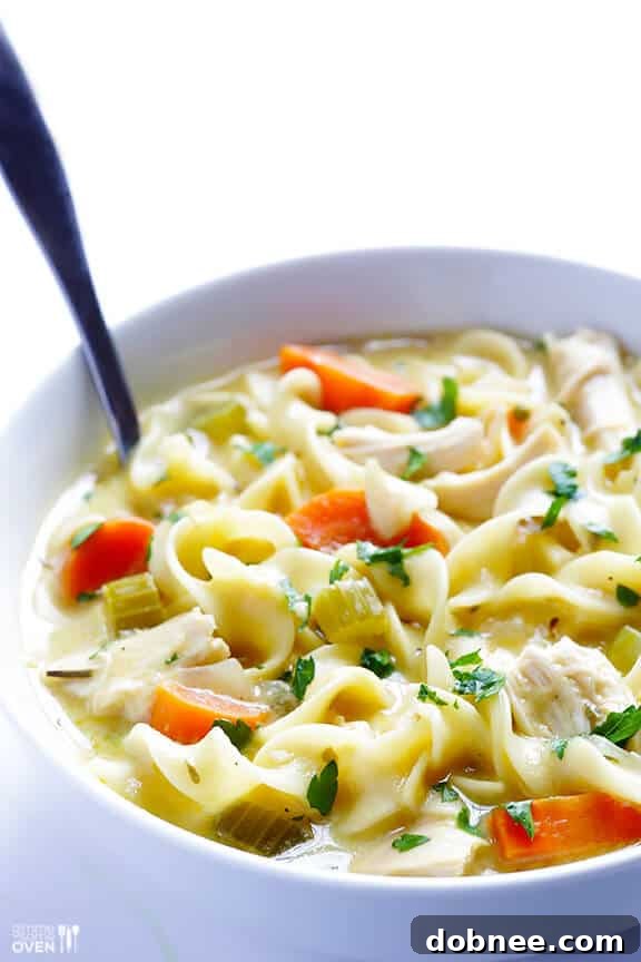 A bowl of creamy chicken noodle soup garnished with fresh parsley.