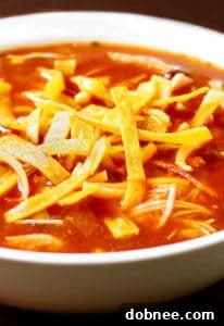 A bowl of Slow-Cooker Chicken Tortilla Soup garnished with tortilla strips and cilantro.