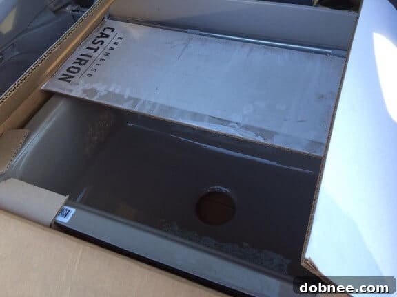 Uninstalled Kohler cast iron sink and touchless faucet in packaging.