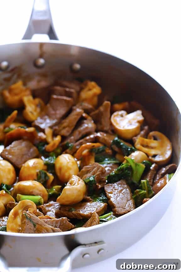The stir-fry cooking in a large pan, showing the beef, mushrooms, and kale coming together with the sauce.
