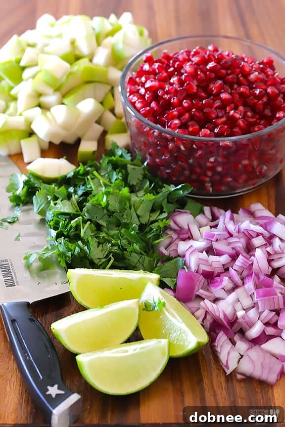 Closeup of fresh pears, pomegranate seeds, red onion, cilantro, and lime for salsa