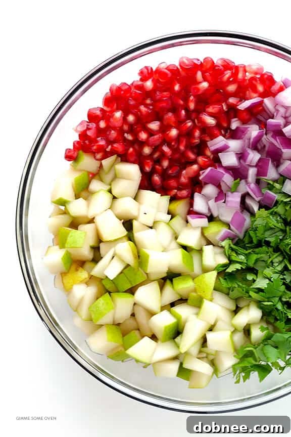 Adding lime juice to a bowl of pear and pomegranate salsa