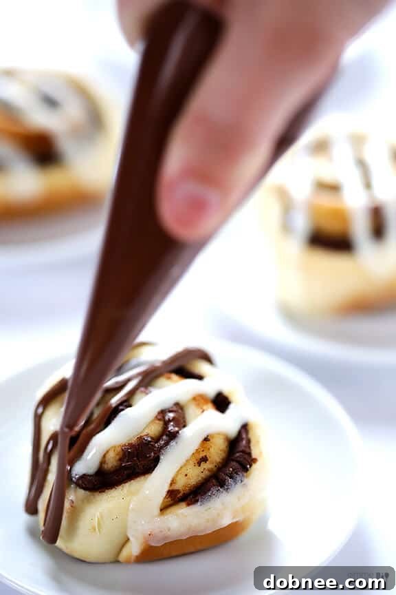 Nutella Cinnamon Rolls drizzled with extra Nutella and additional frosting