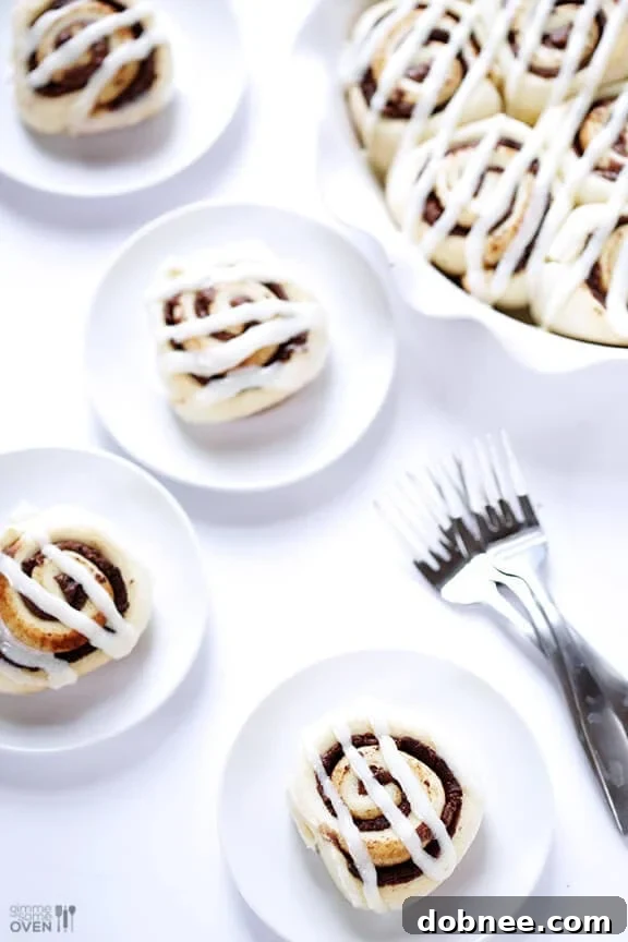 Closeup of warm Nutella Cinnamon Rolls with melted frosting and a drizzle of Nutella