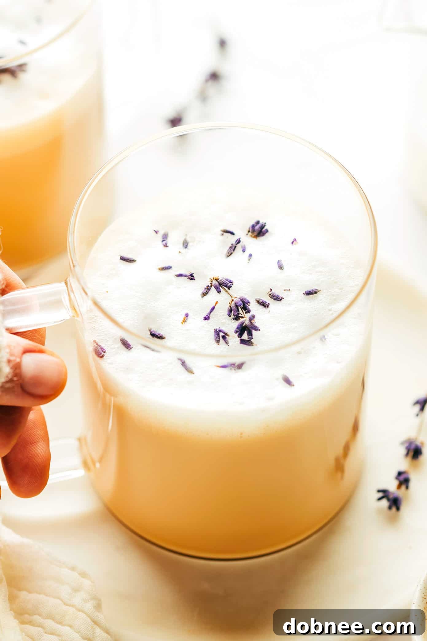 Hand holding a mug of London Fog Latte with frothy milk