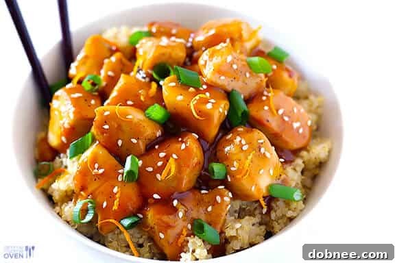 Delicious and healthy Skinny Orange Chicken served over a bed of quinoa, garnished with green onions and sesame seeds.