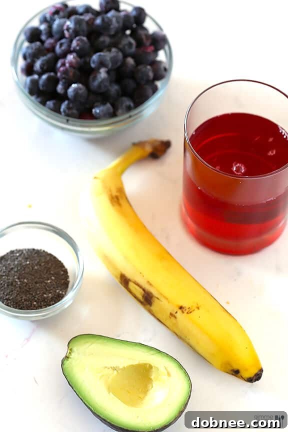 Fresh ingredients laid out for the Brain Power Smoothie: blueberries, avocado, banana, chia seeds, and pomegranate juice.