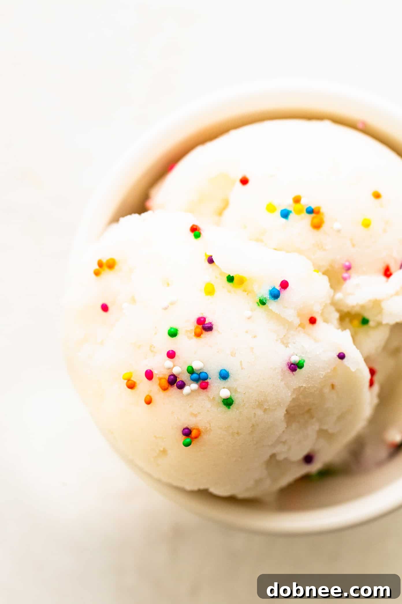 A close-up shot of a scoop of homemade snow ice cream in a small bowl, garnished with colorful sprinkles.