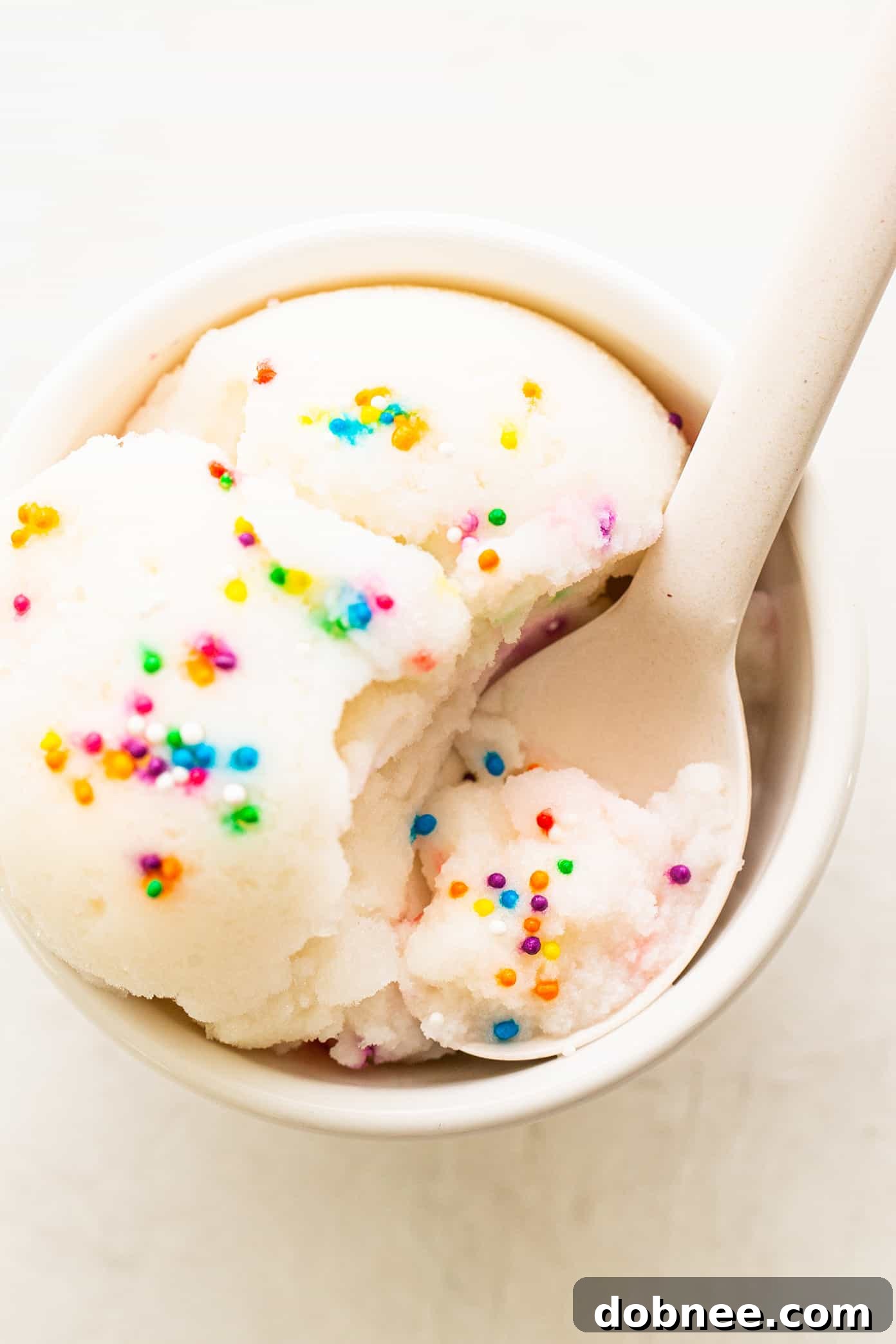A bowl of snow ice cream generously topped with colorful rainbow sprinkles, ready to be eaten.