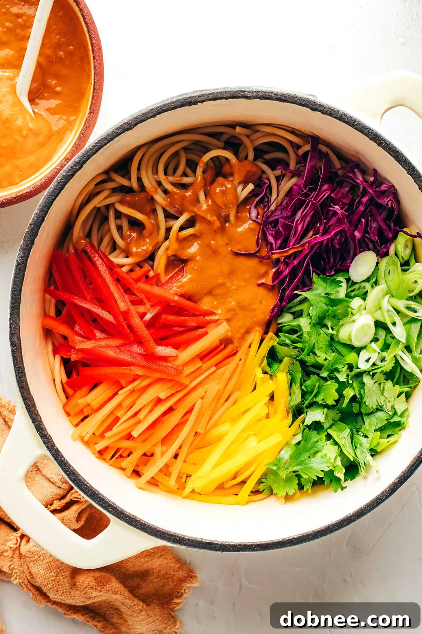 Mixing together rainbow peanut noodles in a large pot