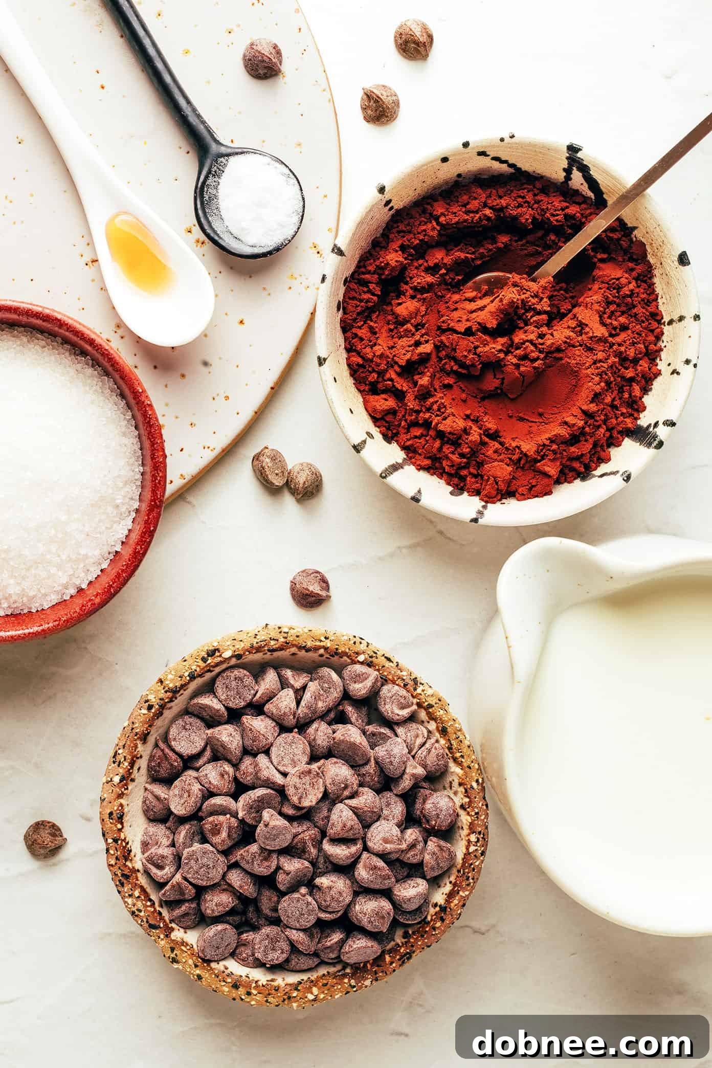 Cozy Cocoa Comfort 3 A close-up of hot chocolate ingredients laid out on a table, including milk, chocolate chips, and cocoa powder.