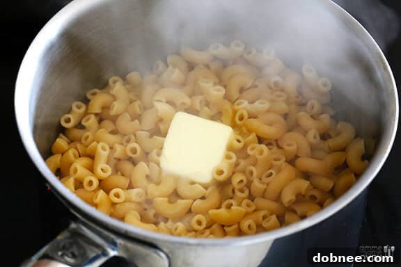 Cooked elbow macaroni with melted butter in a pot, ready for the sauce.