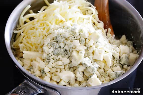Adding crumbled blue cheese and grated sharp white cheddar to the macaroni.