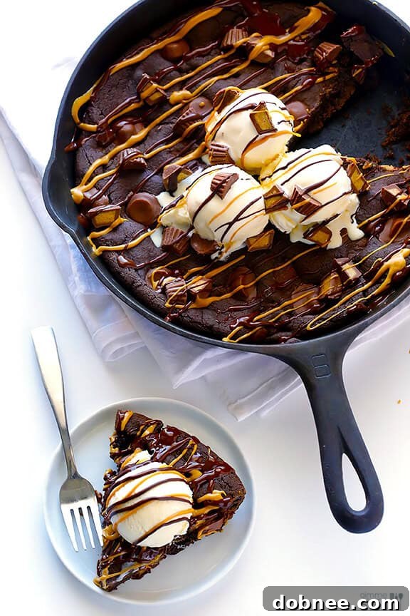 Gooey chocolate peanut butter skillet cookie, topped with ice cream and more peanut butter cups.
