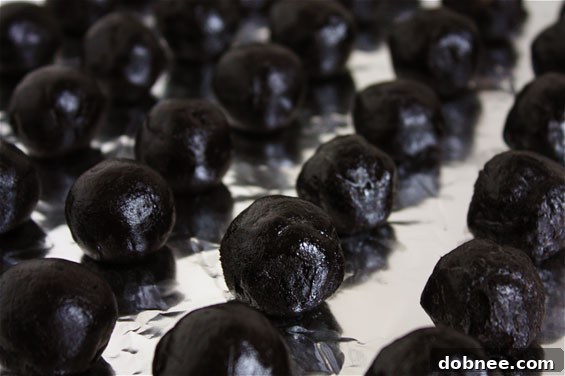 Close-up of freshly made Oreo Truffles, some drizzled with dark chocolate, on a platter.